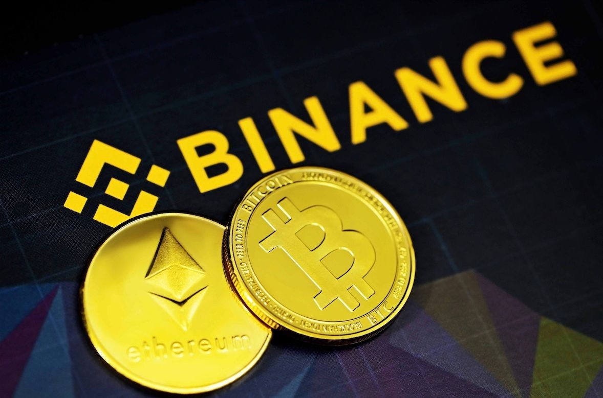 Close-up of Ethereum and Bitcoin coins on a black surface with the Binance logo in the background.